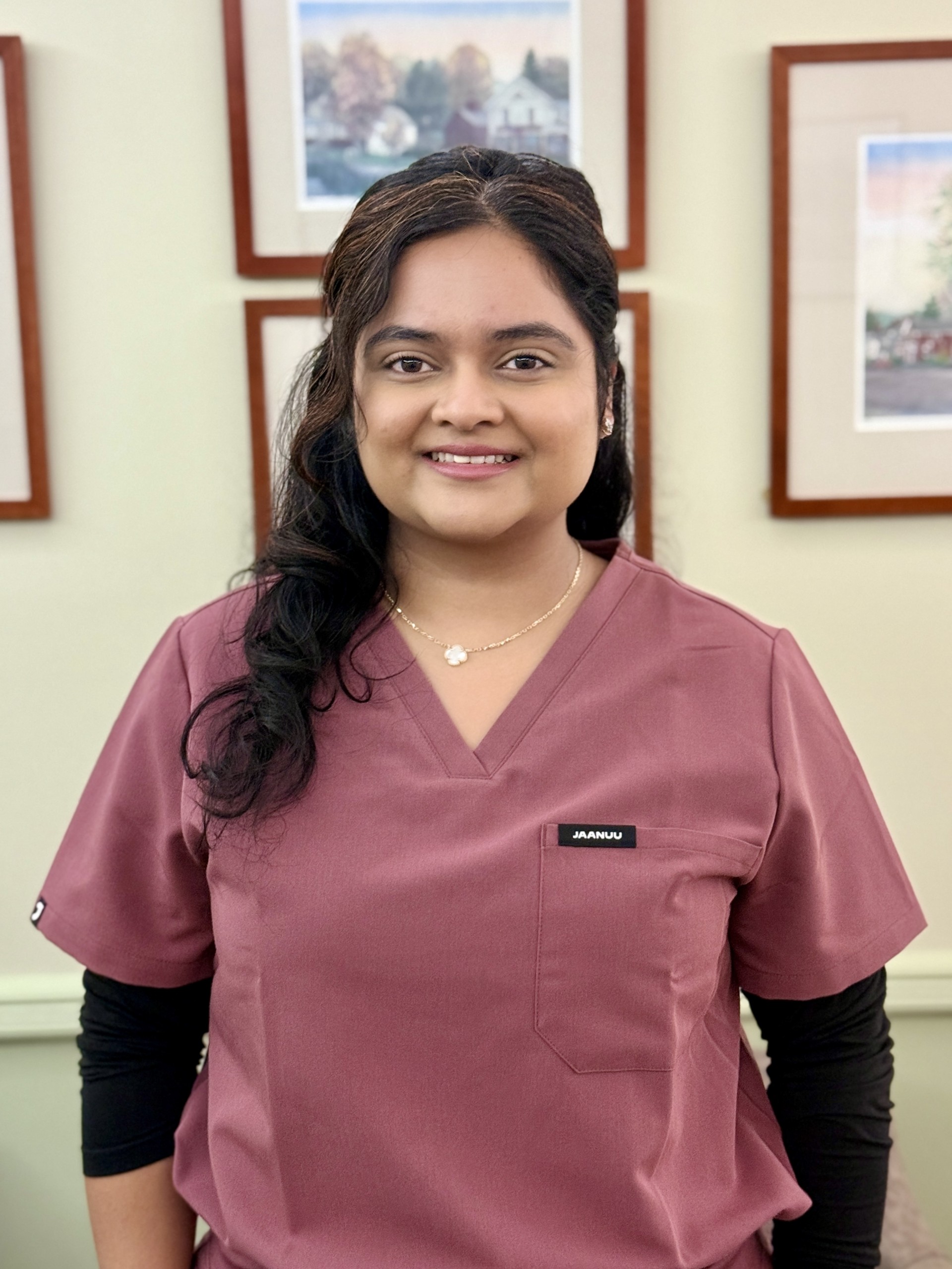 Dr. Krupa Patel smiling in mauve colored scrubs in a dental office setting